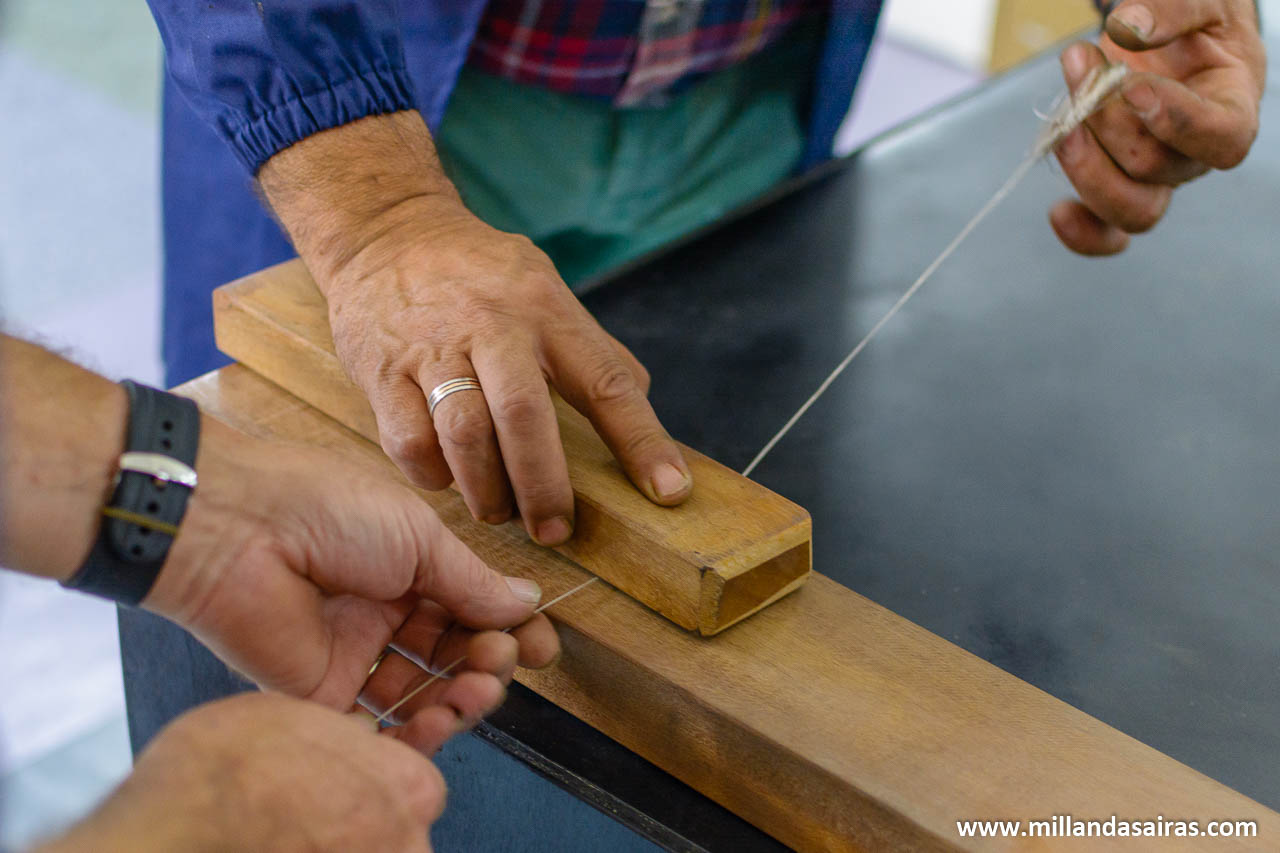 Torsión manual del hilo mediante dos listones de madera consiguiendo hacerlo más fino y más resistente